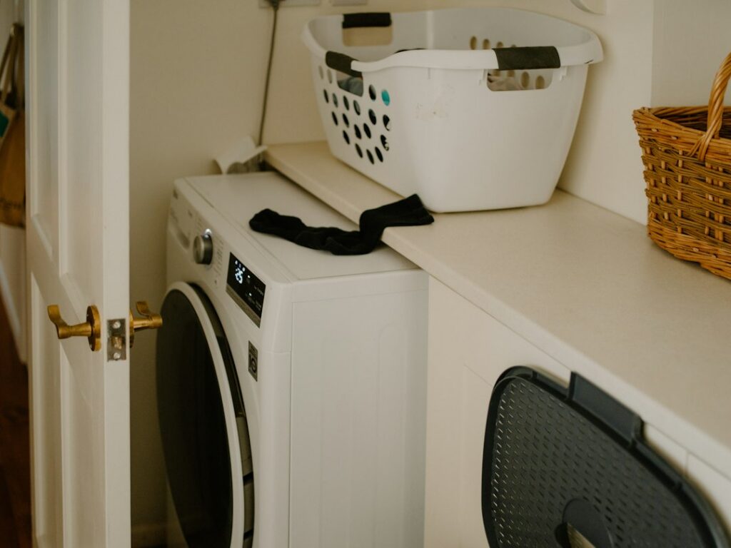 洗濯かごと靴下が置かれた白い洗濯機のイメージ写真